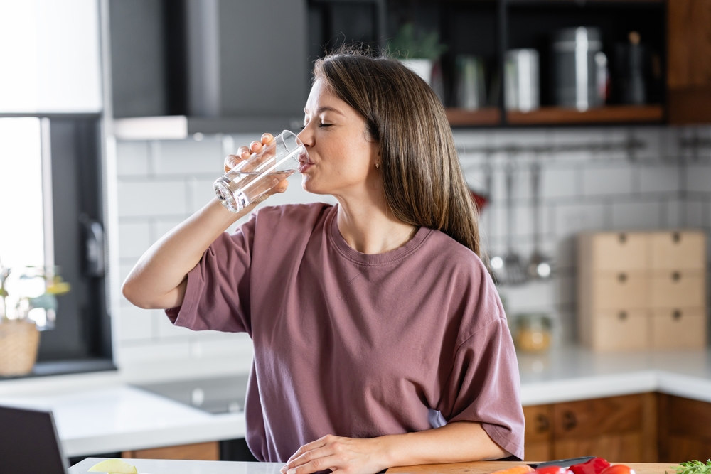 person drinking water from glass