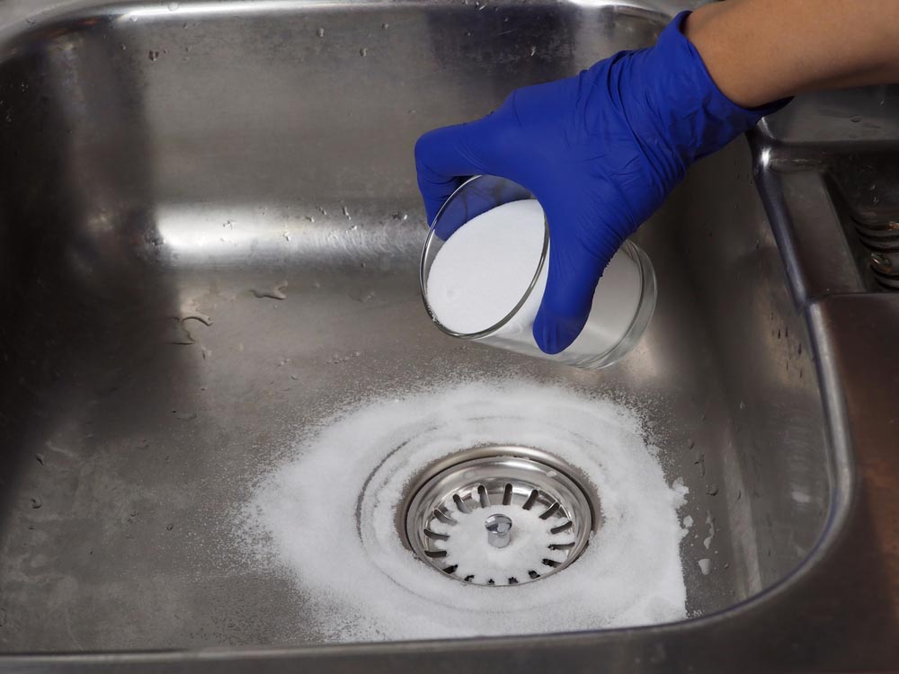 person pouring baking soda down the drain