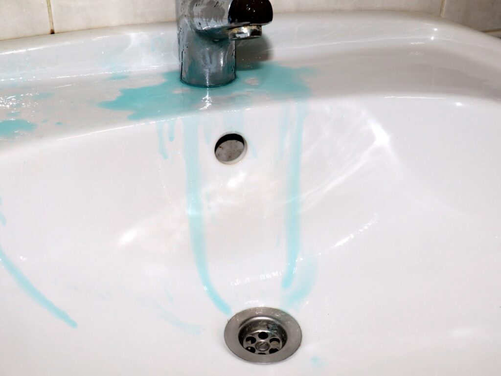 Vibrant blue streaks staining a white porcelain bathroom sink