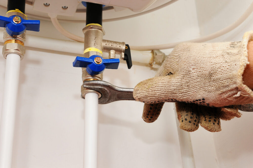 A plumber attaches a hose to a water heater drain valve