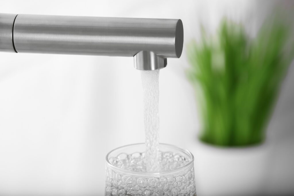 Clear water filling a glass from a kitchen faucet