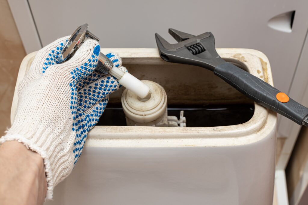 hand-dismantling-flush-mechanism-toilet-tank