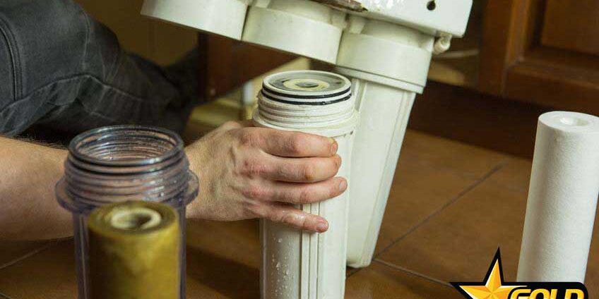 Changing filters in your home water purification system. The master replaces the gut filter in the coal system.